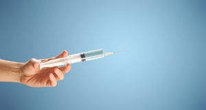 Female doctor hand holding syringe with blue background-1