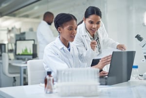 Women in lab look at data - stock image-min