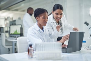 Women in lab look at data - stock image