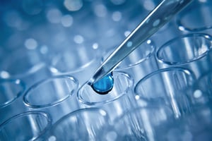 liquid dropping into test tube - stock image